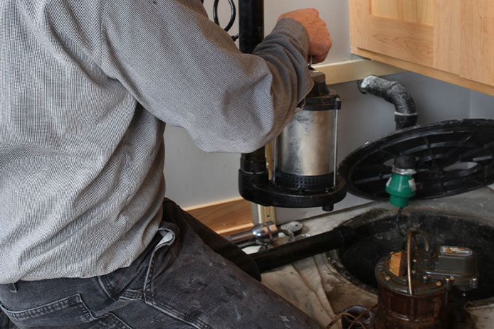 Plumber installing sump pump